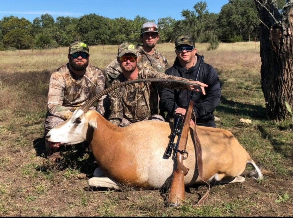 Four hunters with LWE caps posing behind trophy Scimitar-horned Oryx and precision rifle