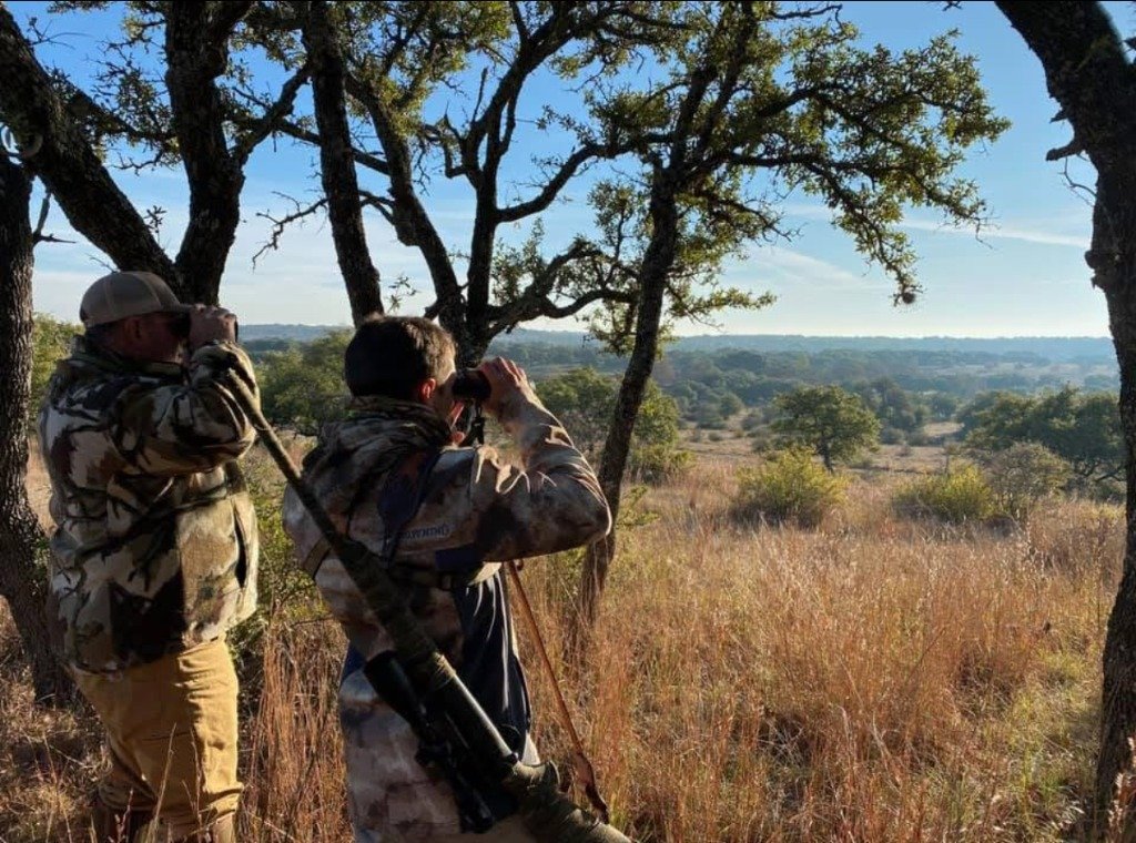Two hunters glassing prime Texas hunting terrain at sunrise